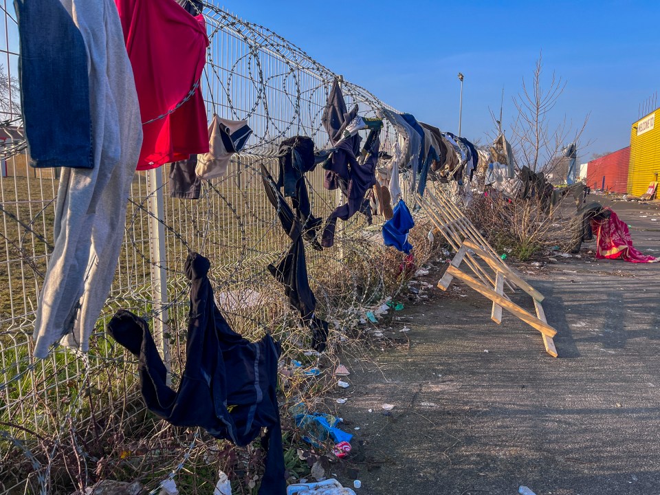 Clothing hanging on a barbed wire fence near a migrant camp.