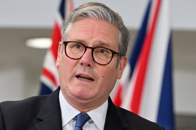 Sir Keir Starmer stood in front of some British flags.