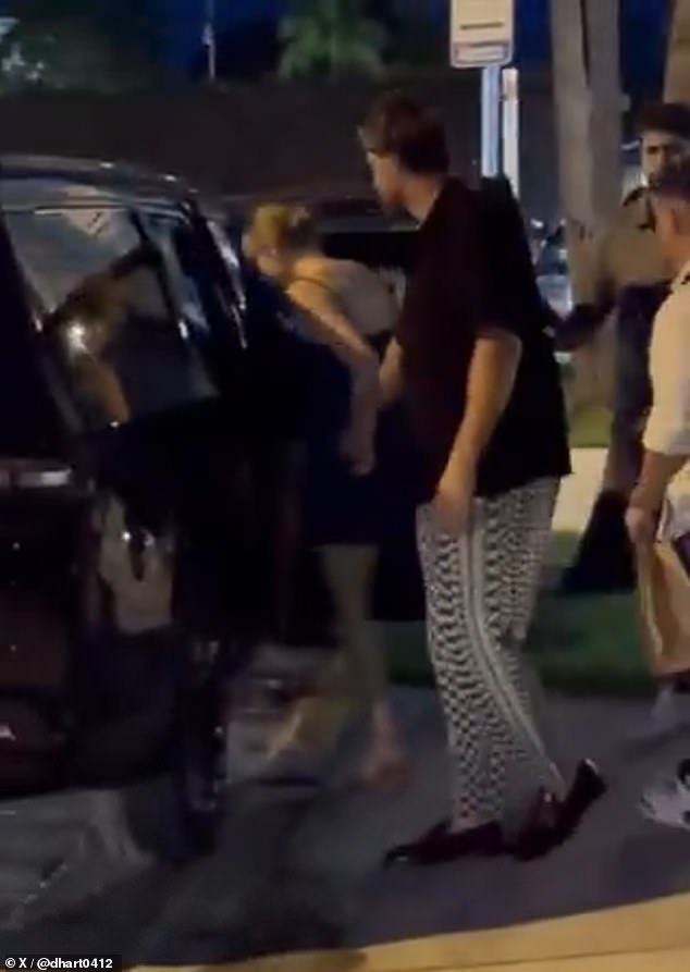 Holding hands with the NFL star, Swift greeted awaiting fans with a smile before getting into the front passenger's seat of a black SUV