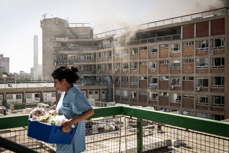 A nurse carries medical supplies past a building with smoke billowing out at Soroka hospital after it was struck by an Iranian missile. Photograph: JOHN WESSELS/AFP via Getty Images