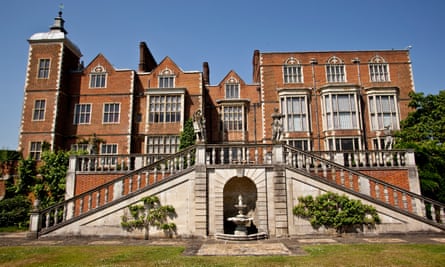Hatfield House, viewed from the front, is photographed on a sunny day, its grand red facade against blue skies.