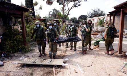 Israeli soldiers carry the body of a victim of an attack by militants from Gaza at Kfar Aza kibbutz in southern Israel, 10 October