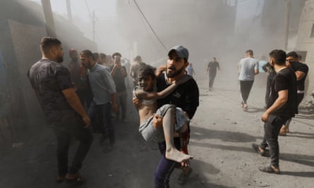 A Palestinian man carries a child casualty at the site of Israeli strikes on houses in Khan Younis in the southern Gaza Strip 