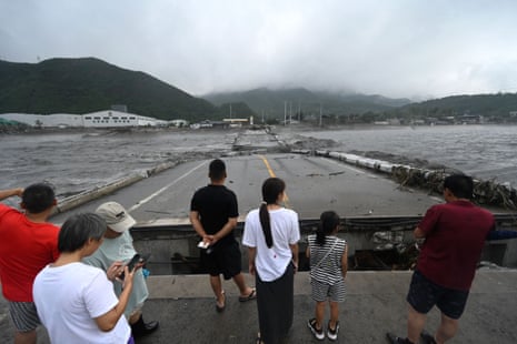People look at a collapsed bridge on the Dashihe River after heavy rains in the Fangshan district in Beijing on 1 August