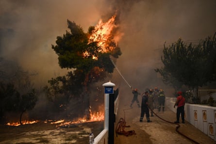 A firefighter sprays water on flames during a wildfire in Chasia in the outskirts of Athens, 22 August.