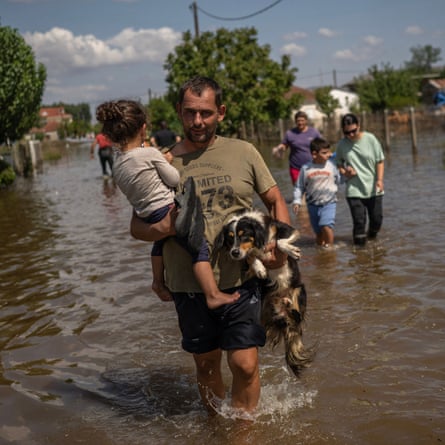 A man carries a girl and a dog in the flooded village of Palamas near the city of Karditsa, central Greece, 8 September after deadly storms in which more than a year’s worth of rain fell in 24 hours 