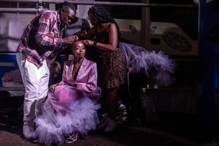 A model is helped by assistants to get a design ready at the backstage of the main show of the Kibera Fashion Week, 15 October