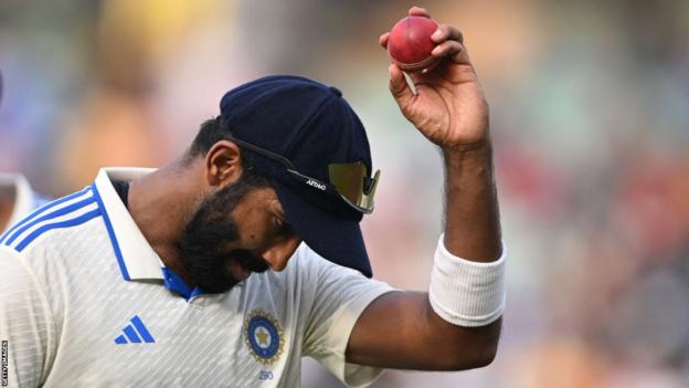 India fast bowler Jasprit Bumrah holds up the ball as he walks off after taking 6-45 against England