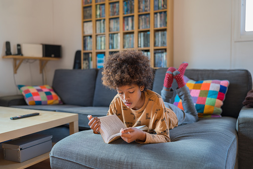 African- American boy reading a book on the sofa