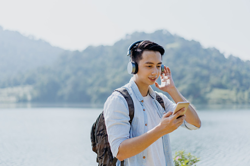 Young hiker enjoying music with wireless headphones at outdoor
