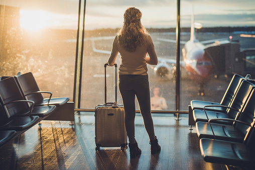 Rear view of curly female at airport.