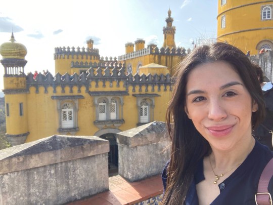A selfie of Angela in front of a yellow castle