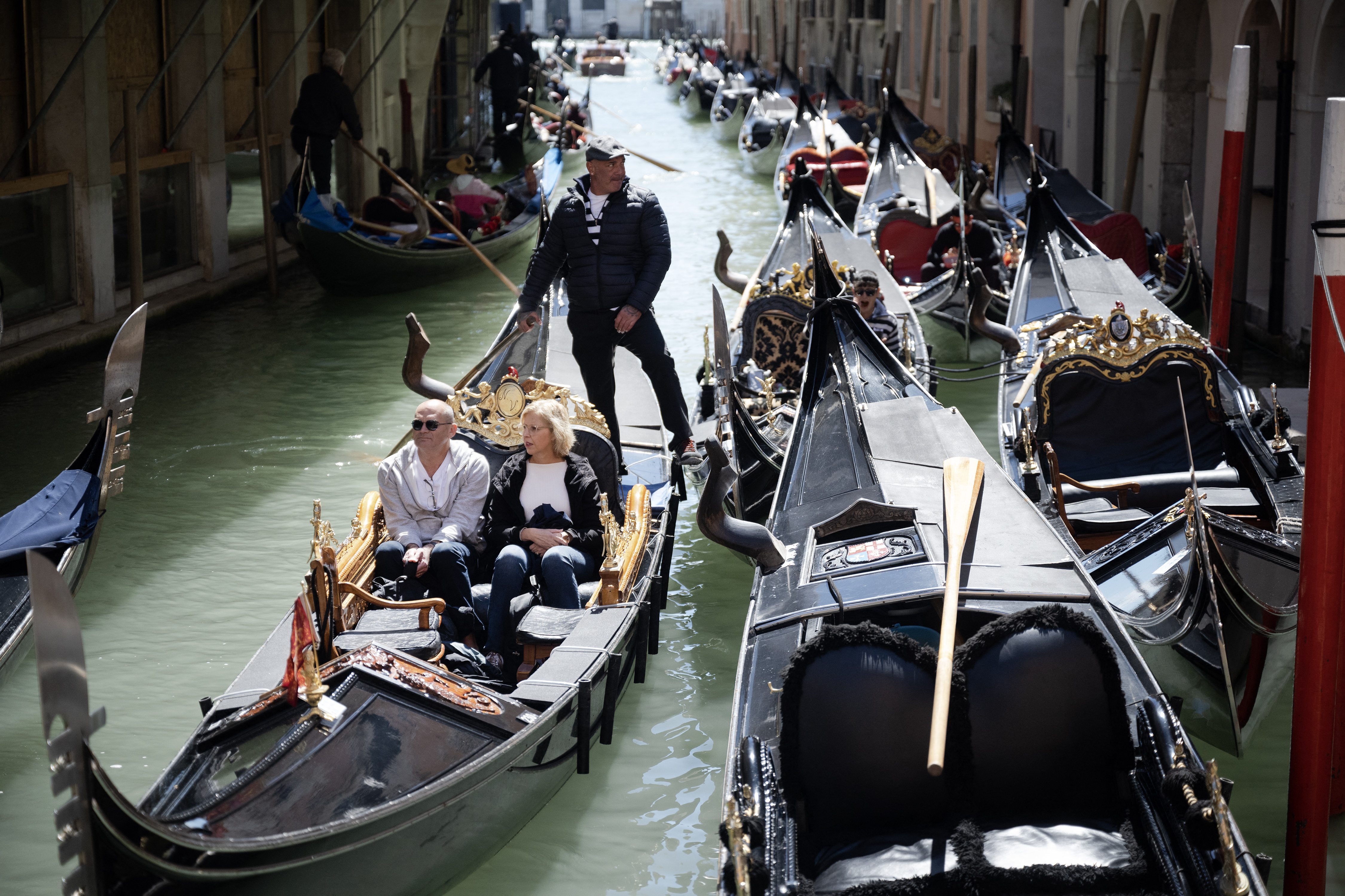A gondolier sails with two customers near San Marco Square in Venice today