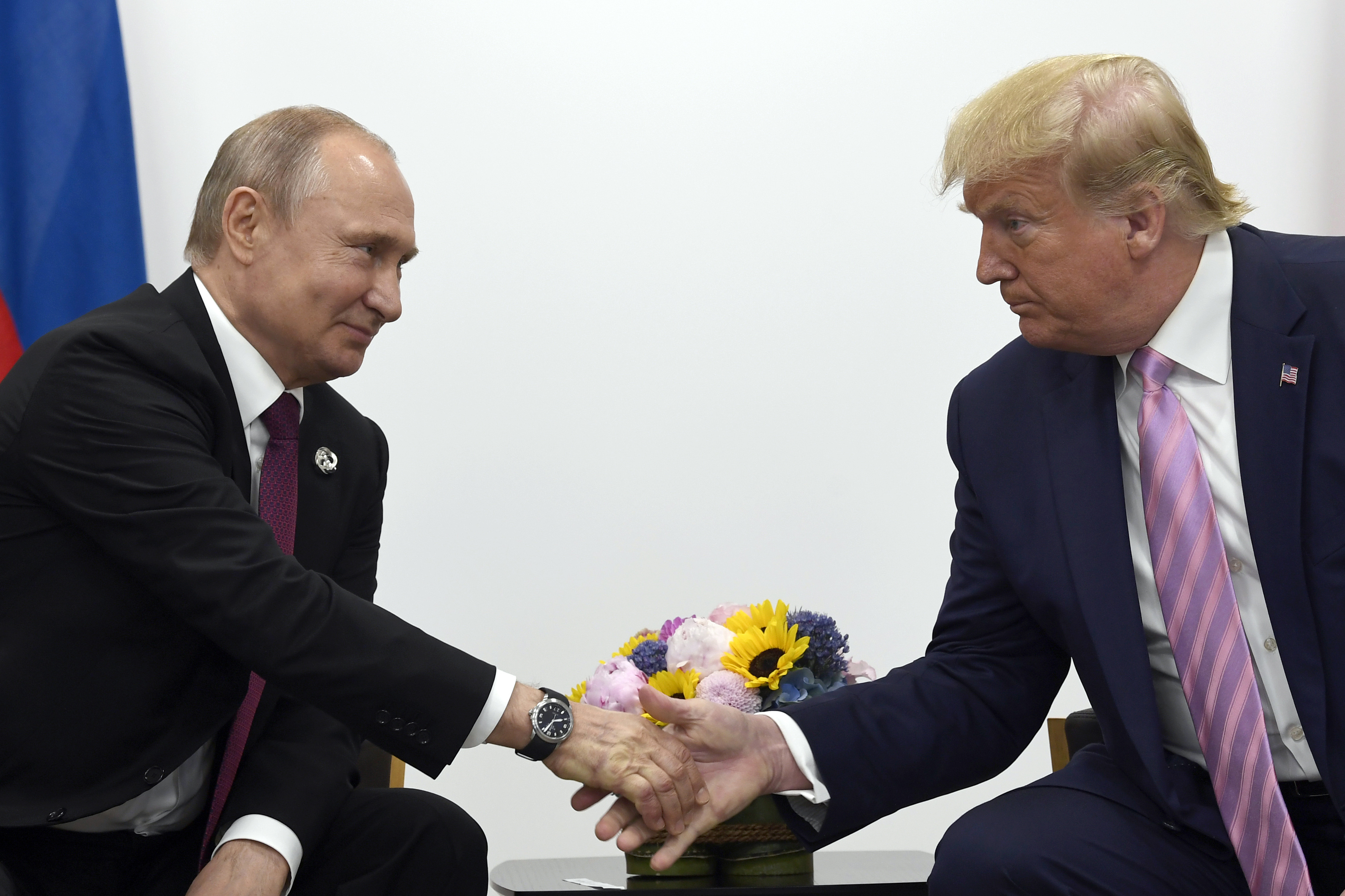 Former US president Donald Trump, right, shaking hands with Russian President Vladimir Putin