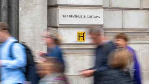 Pedestrians walk past the entrance to the HMRC offices in London