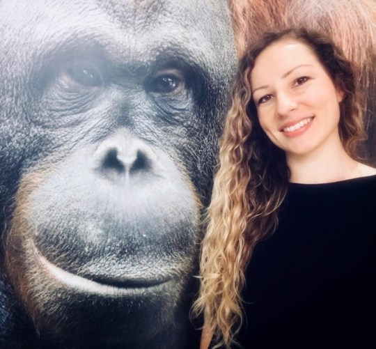 Dr Isabelle Laumer stood next to a photo of Rakus the orangutan