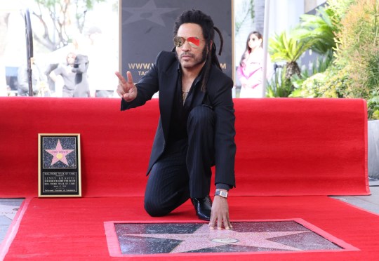 Lenny Kravitz touching a star on thr Hollywood Walk of Fame