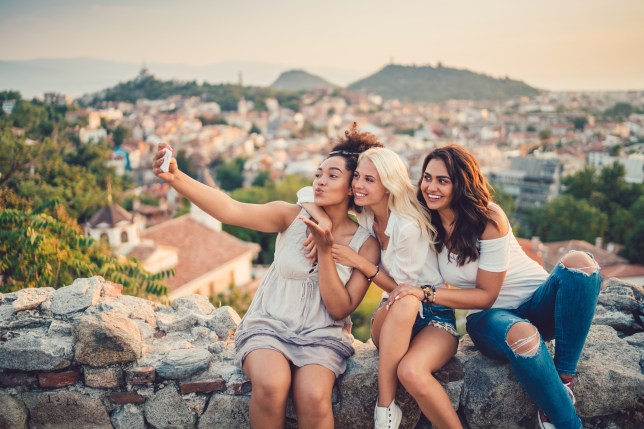 Women taking selfies against the cityscape