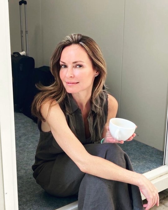 A recent photo of Sharon Corr sitting in a doorway with a cup of tea