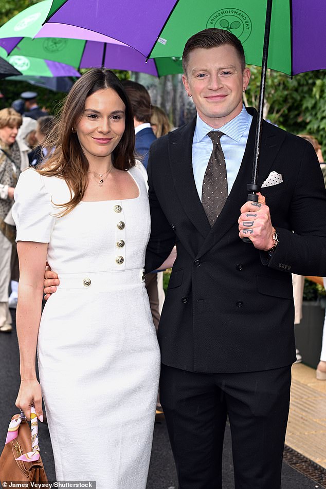 Holding an umbrella over the two of them, Adam, 29, looked rather dapper in a smart black suit and brown white spotted tie and hanker chief