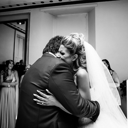 Sophie Hinchliffe in her wedding dress and veil as she hugs her father Alan