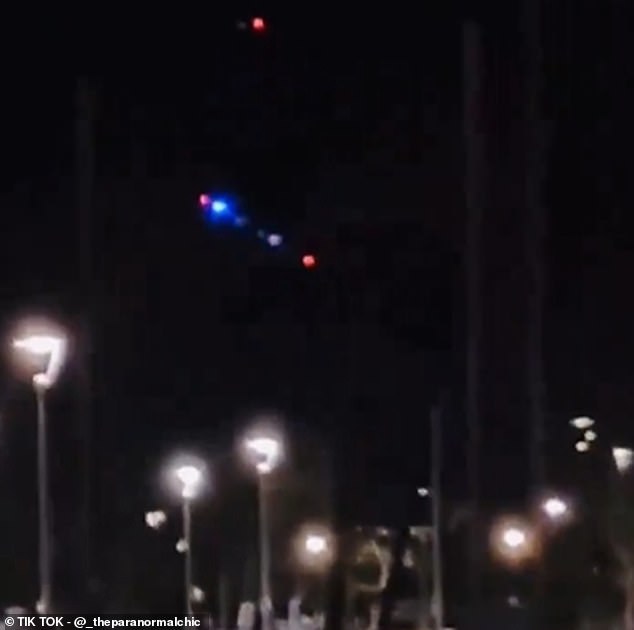 In this video, a woman can be heard saying 'Oh, my God. It's landing!' as she appears to film the red-and-blue light UFO gliding slowly toward a marina dock below. Experts told DailyMail.com that the footage was likely taken from Hawaii - not California