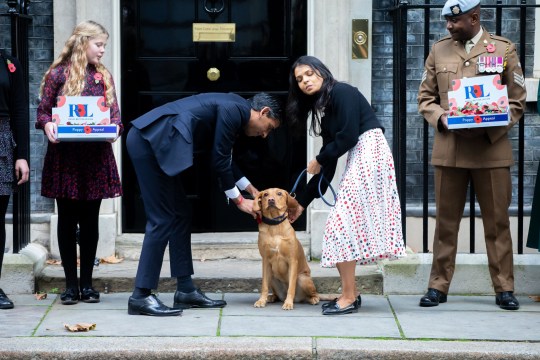 UK Prime Minister Rishi Sunak and wife Akshata Murthy stand on either side of their dog Nova outside No 10 Downing Street