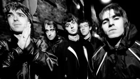 Getty Images A black-and-white photo of the original Oasis line-up in 1993. Left to right: Noel Gallagher, Paul Arthurs (aka Bonehead), Paul McGuigan, Tony McCarroll,Liam Gallagher