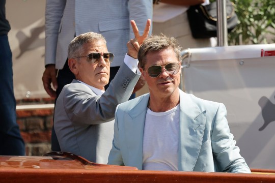 George Clooney putting two fingers behind Brad Pitt's head at Venice International Film Festival