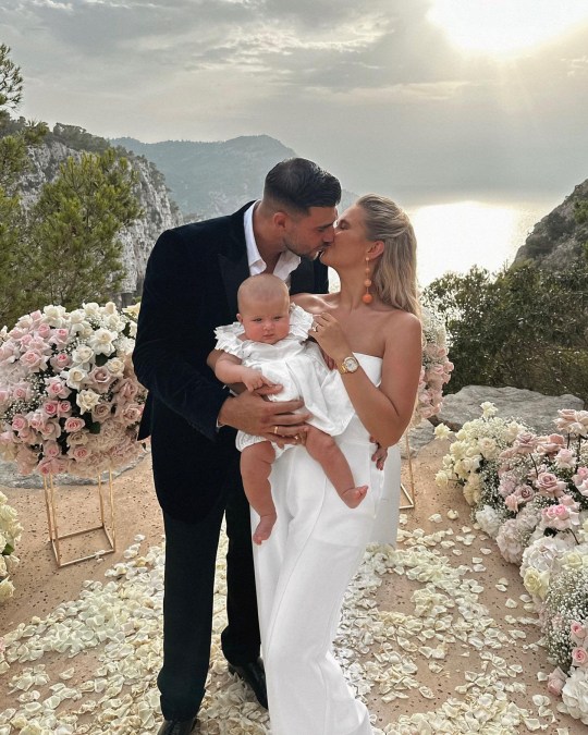 Tommy Fury and Molly-Mae Hague kissing while holding their daughter Bambi after getting engaged.