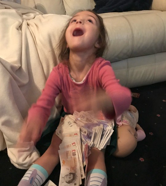 Mindy's daughter laughing, with a wad of notes on her lap