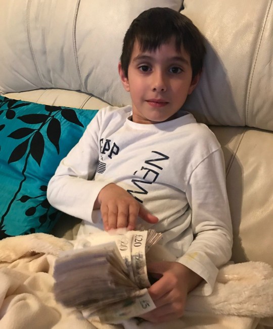 Mindy's son holding a wad of cash while sitting on the sofa