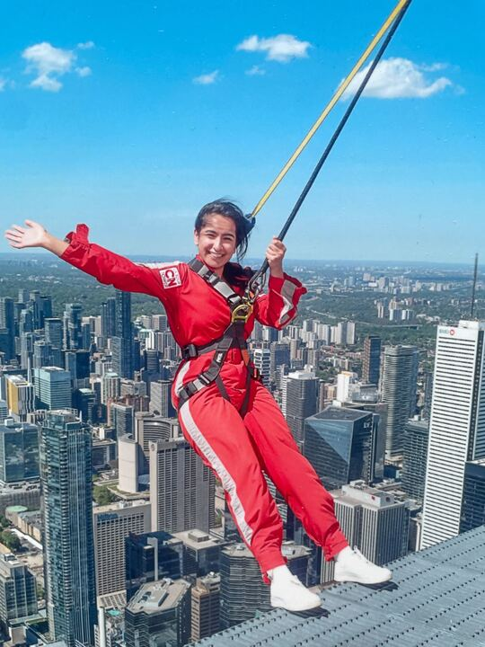 Reporter Hiyah Zaidi leaning back on the CN tower