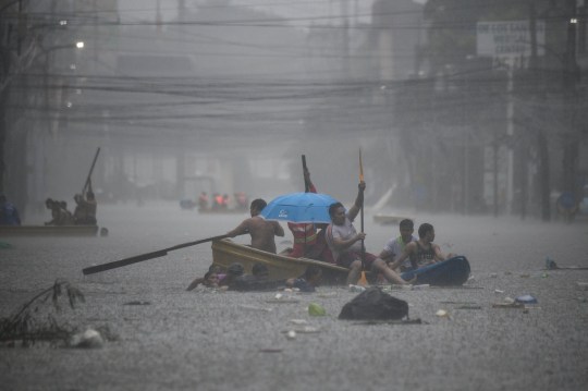 TOPSHOT - Rescuers paddle their boats along a flooded street in Manila on July 24, 2024 amid heavy rains brought by Typhoon Gaemi. Relentless rain drenched the northern Philippines on July 24, triggering flooding in Manila and landslides in mountainous regions as Typhoon Gaemi intensified the seasonal monsoon. (Photo by Ted ALJIBE / AFP) (Photo by TED ALJIBE/AFP via Getty Images)