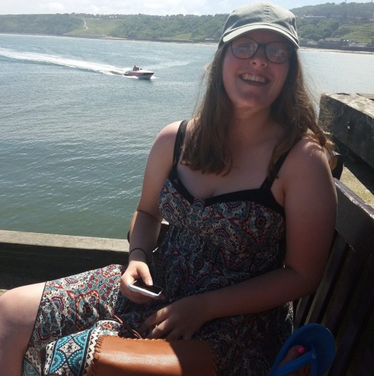 Jesse sitting by the sea and smiling