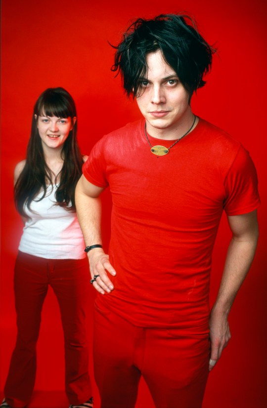 The White Stripes' Jack White and Meg White stand together with red background 