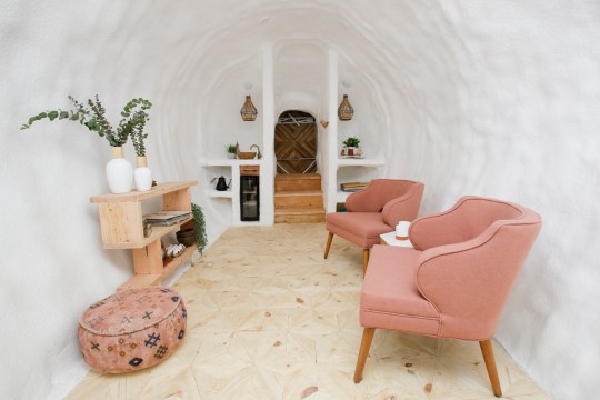 Inside the Big Idaho Potato Hotel, which has white walls, a wooden shelf, and two pink chairs