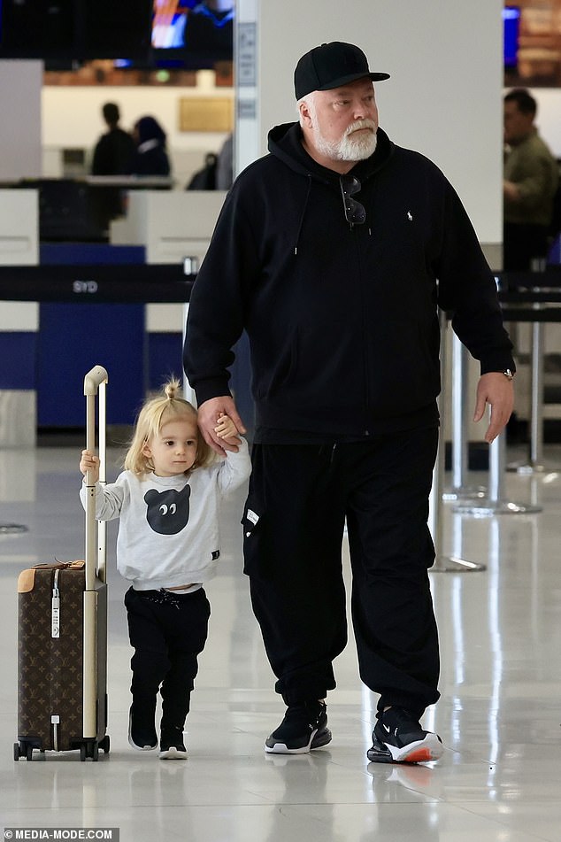 The radio shock jock sported his signature black baseball cap and looked every inch the doting father as he walked through the airport holding hands with his son Otto