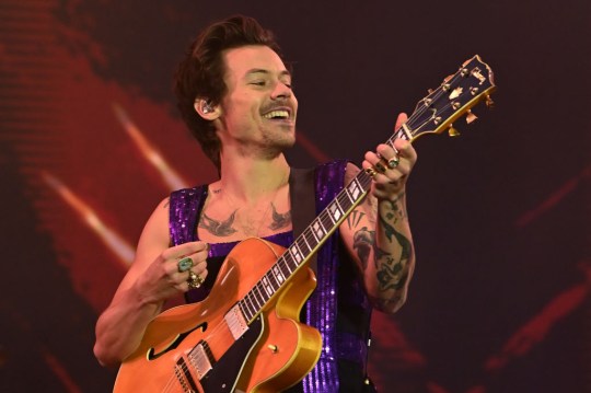 Harry Styles plays guitar on stage