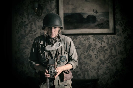 Kate Winslet as Lee Miller in Lee holding a camera and dress in an army uniform