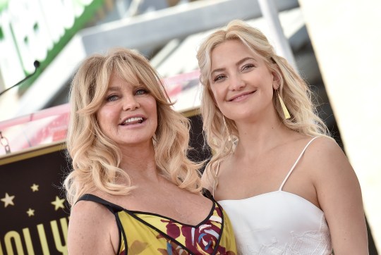 Kate Hudson and Goldie Hawn smile as they pose together at an event