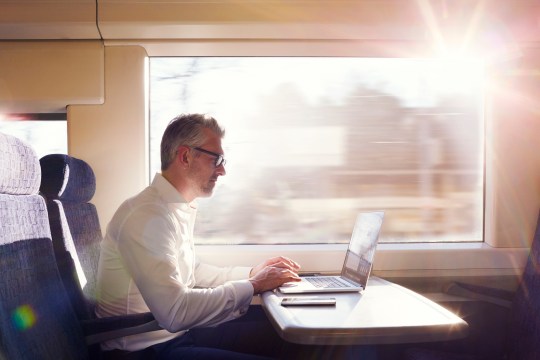 Businessman working on a laptop on a commuter train.