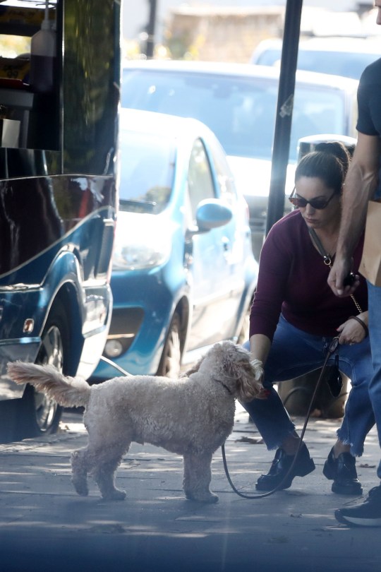 Kelly Brook bends down to pat her dog inLondon street