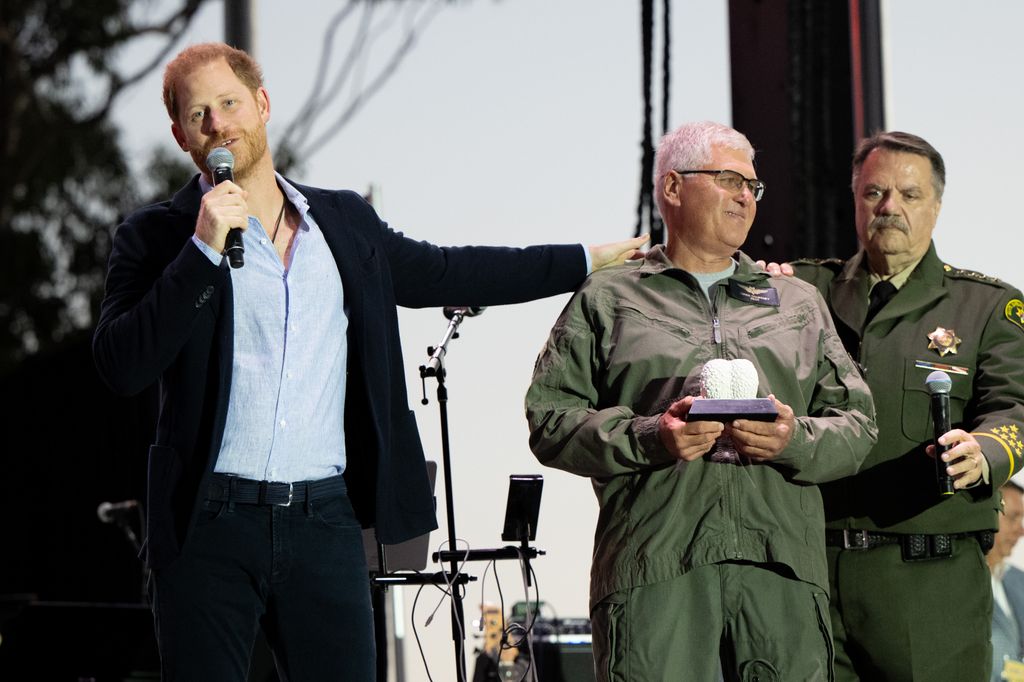 Prince Harry, Duke of Sussex (L) presents an award to Santa Barbara County Air Support Pilot Loren Courtney during the One805Live Fall Concert on September 20, 2024 