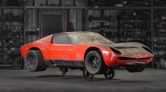 Front and side of red car with dust. CALIFORNIA, USA: THREE FORGOTTEN Lamborghini Miuras found in a junkyard are heading to auction for ??1.5m. Pictures show three examples of what is considered to be the world???s first supercar, covered in dust, at a junkyard belonging to renowned collector Rudi Klein who died in 2001. The cars will be auctioned at the end of October through RM Sotheby???s. This is one of the world???s most secret car collections, which is for the first time being auctioned off by RM Sotheby???s in its ???The Junkyard: The Rudi Klein Collection??? sale. For lovers of Lamborghini???s iconic V-12-engined, Bertone-designed Miura, the auction will include not one, but three restorable examples. One of the most significant examples of the three, is a 1968 Miura P400, believed to have been first owned by Lamborghini engineer and test driver Claudio Zampolli. According to mediadrumworld.com, Zampolli shipped the car to Southern California in the 1970s, with Rudi Klein???s Porche Foreign Auto Wrecking company acquiring the car in 1978. The Miura was initially presented as a rolling chassis at the 1965 Turin Motor Show, drawing considerable customer interest, and four months later a fully clothed prototype was unveiled at the 1966 Geneva Salon. Miura P400 had 350 horsepower and could reach 170 mph and it was built in a modest quantity of just 275 examples through 1970, when it was superseded by the upgraded P400. The car listing is held by RM Sotheby's who commented on the listing. ???Though the Miura would become increasingly powerful with forthcoming iterations, none were as pure and novel as the original P400,??? reads the listing. ???It is, without exaggeration, one of the true paragons of sports car design, and a blue-chip collectible of unanimous merit. ???Originally finished in Giallo Miura over an interior upholstered in Bleu leatherette, this example was specified for the Italian market and equipped with instruments in kilometers. ???The Miura was officially dispatched from the factory to the dealer Lamborcar in March 1968, and the customer of record is listed only as Mr. Zampolli. ???Zampolli also imported Lamborghinis to Southern California, which might explain how this car came into the possession of Rudi Klein by the late 1970s. ???While this is merely conjecture, we know that the Miura was on the premises of Porche Foreign Auto Wrecking by March 1978, as reflected by a handful of dated photo prints on file. ???By then painted in the current shade of bright aqua green, the Miura went into a period of extended storage no shorter than 46 years, from which it now finally emerges. ???For the true purist of automotive archaeology, who would be so bold as to oversee a major rejuvenation, there could hardly be a more inviting prospect.??? mediadrumimages / @RMSothebys