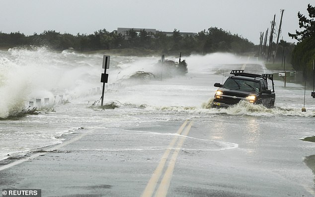 A truck (right) slides over a flooded road in Southampton, New York, during Hurricane Sandy