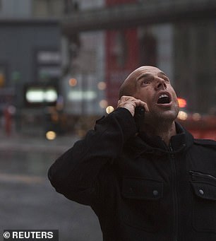 Above, a pedestrian looks up after a crane partially collapses - hanging from a high-rise in Manhattan as Hurricane Sandy makes its approach into New York on October 29, 2012