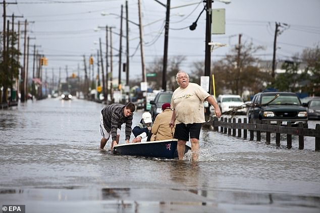 'If Superstorm Sandy had occurred in 1912 instead of 2012, it would have likely not flooded Lower Manhattan,' Fox discovered while writing his book. Above, locals use a small boat to wade through flooded streets in Queens' Breezy Point neighborhood during Sandy