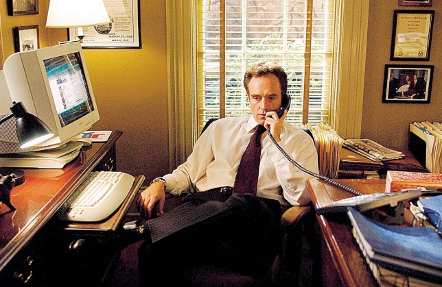 Bradley Whitford as Josh Lyman in The West Wing, at an office desk on the phone