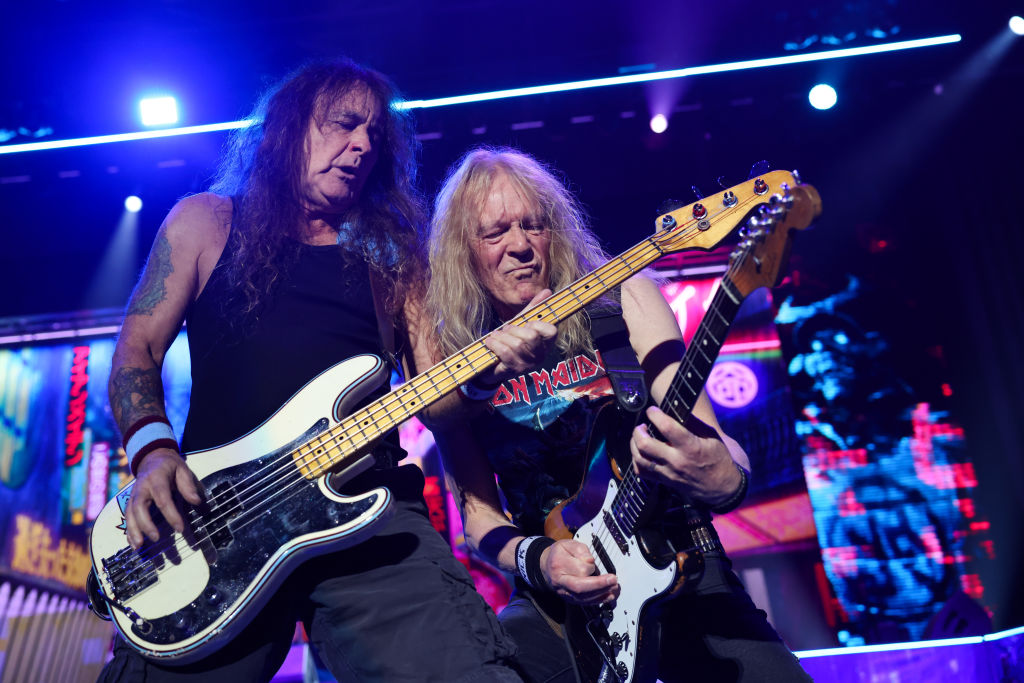 Steve Harris and Janick Gers of Iron Maiden perform on stage together. Both are close to camera playing guitars.